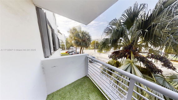 View from a building balcony overlooking palm trees and a street.