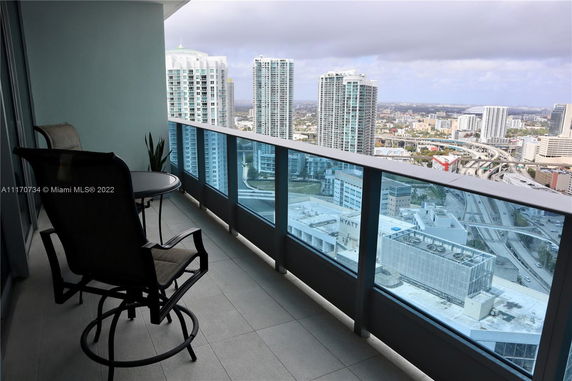 Balcony view from a high-rise building overlooking a cityscape with skyscrapers and roads.