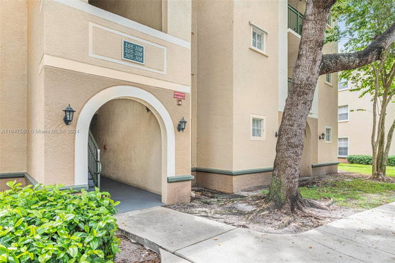 Front view of a multi-story building entrance with an archway and visible apartment numbers.