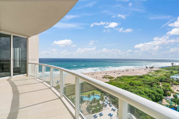 Balcony view of a beach and ocean from a tall building.