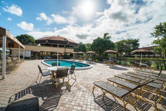 Outdoor swimming pool with surrounding lounge chairs and umbrellas.