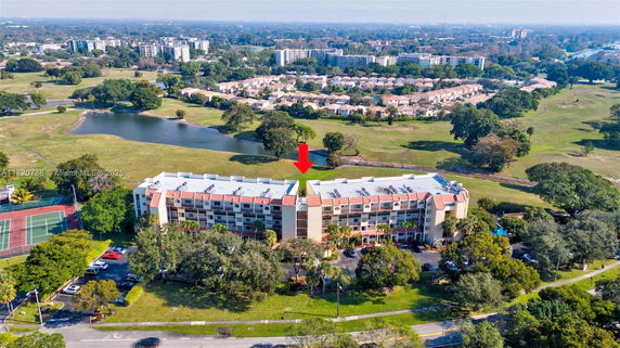 Aerial view of a multi-story residential building surrounded by greenery and recreational areas.