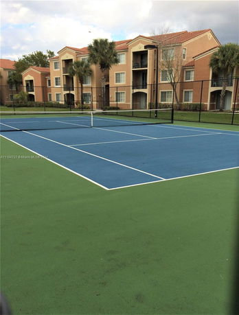 Tennis court in front of a multi-story residential building.
