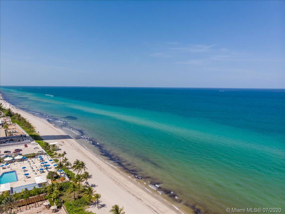 Panoramic view of a beachfront with clear blue ocean and sandy beach.