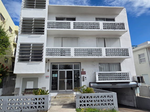 Front view of a multi-story building with decorative concrete block balustrades and jalousie windows.