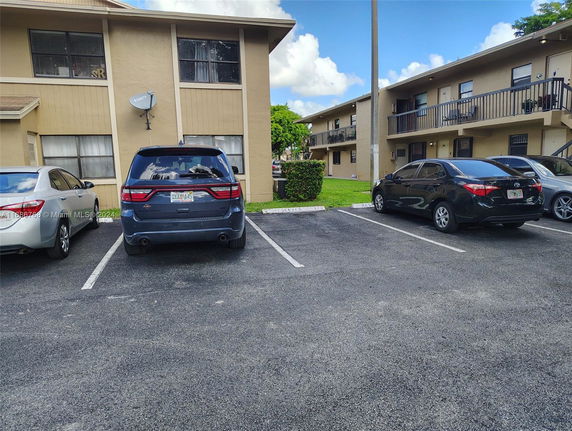 Outdoor parking area in front of a two-story apartment building.