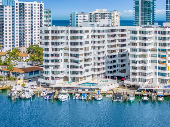 Aerial view of waterfront buildings with nearby boats docked at a marina.