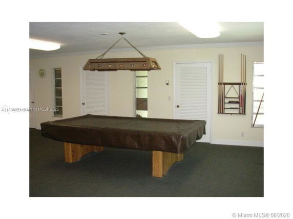 Room with a covered pool table and pool cue rack on the wall.