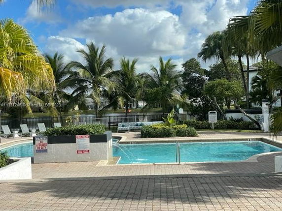 Outdoor swimming pool with surrounding palm trees and lounge chairs.