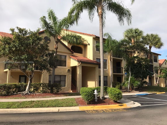 Front view of a multi-story residential building with balconies and red-tiled roof.