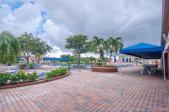 View of an outdoor swimming pool area with blue canopies and surrounding seating.