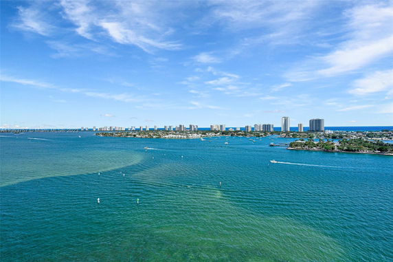 Wide view of a body of water with boats and distant city skyline on the horizon.