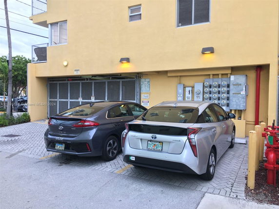 Outdoor parking area with two cars parked in front of a building.