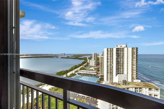 View from a high-rise building overlooking the ocean and other nearby buildings.