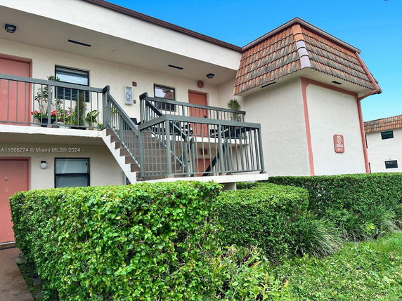 Front view of a two-story residential building with an outdoor staircase and balcony.