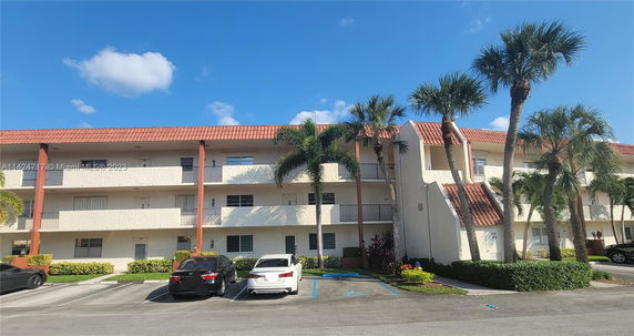 Front view of a three-story residential building with balconies and a terracotta roof.