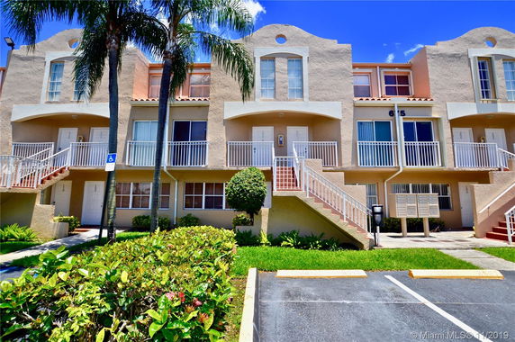Front view of a multi-unit residential building with two stories and staircases leading to each entrance.