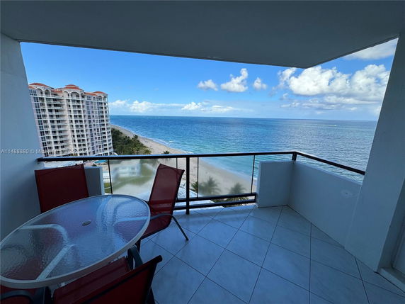 Balcony view overlooking the ocean and nearby high-rise buildings.