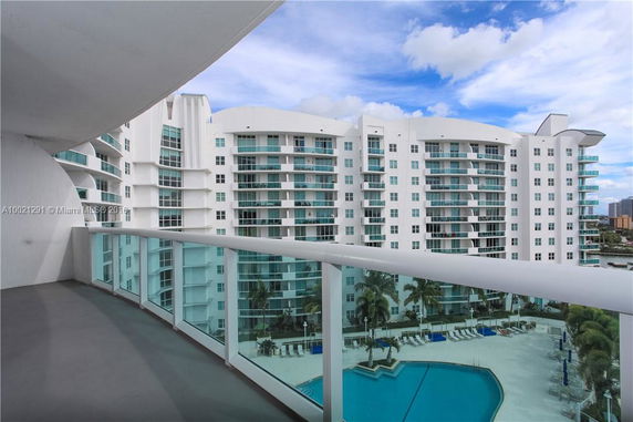 Panoramic view from a balcony overlooking a modern high-rise building with white exterior and multiple balconies.