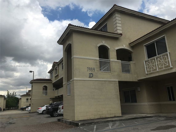 Front view of a multi-story apartment building with balconies and arched windows.