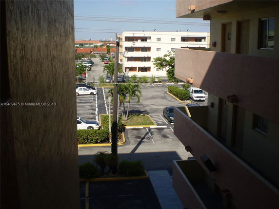 View of a parking area and adjacent residential buildings seen from a balcony.