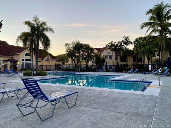 Swimming pool area with lounge chairs and surrounding trees.