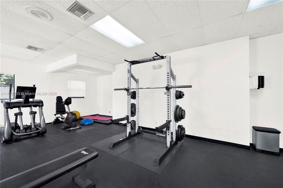 Indoor gym area with exercise equipment including weights and machines.