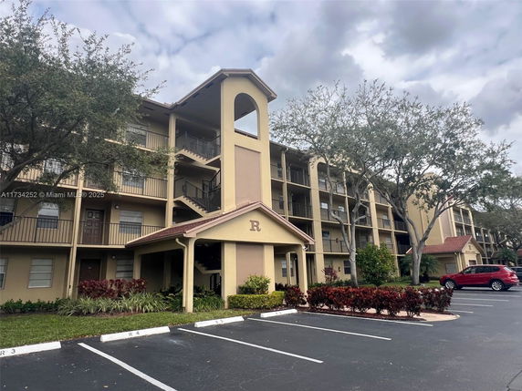 Front view of a multi-story residential building with balconies and covered entrance.