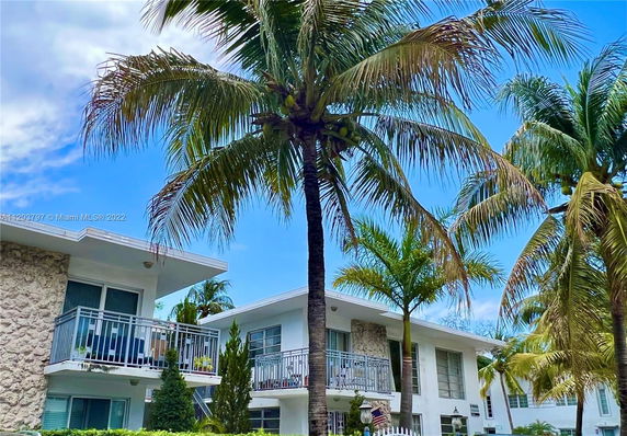 Front view of a two-story building with balconies and palm trees.