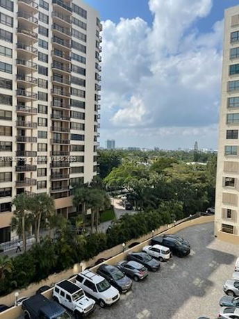 Outdoor view of a building with adjacent open parking area filled with cars.
