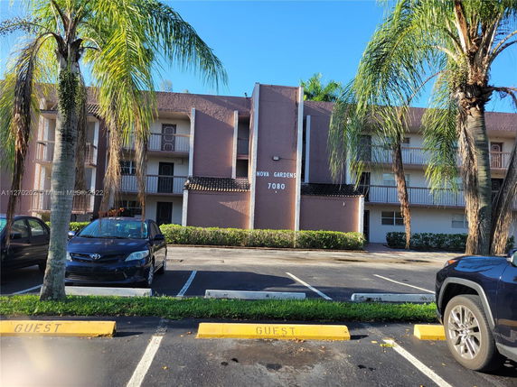 Front view of a multi-story residential building with balconies and parking area.
