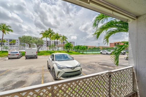 Outdoor parking area with cars and palm trees in the background.