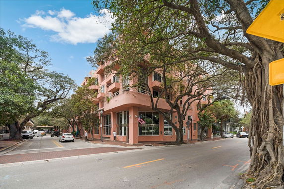 Street view of a multi-story residential building with balconies and large windows.