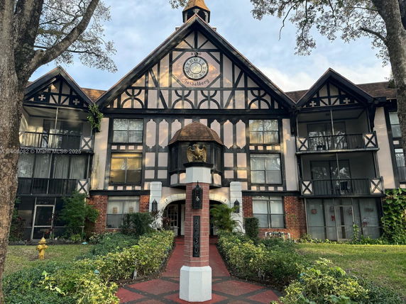 Front view of a multi-story building with a clock on the gable.