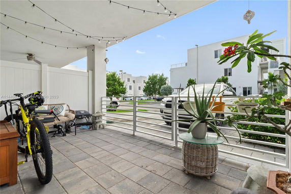 View from a porch area with string lights and outdoor furniture, overlooking a parking area with modern white buildings.