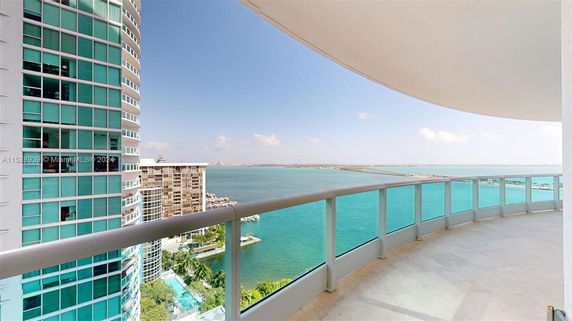 View of high-rise buildings with a curved balcony overlooking a large body of water.