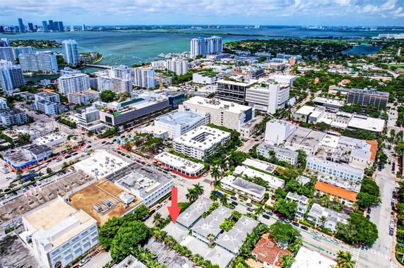 Panoramic view of a cityscape with numerous buildings and a large body of water in the background.