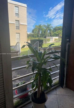 View of surrounding areas seen from a building window, showing a pathway, plants, and part of another building.