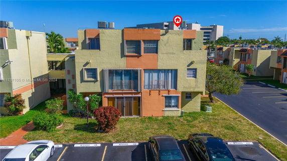 Front view of a multi-story apartment building with parking area.