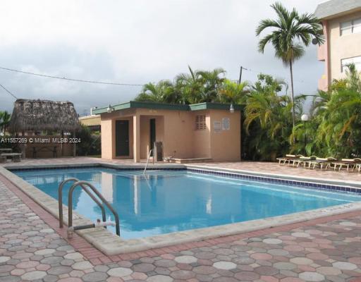 Outdoor swimming pool with a small building nearby and lounge chairs around it.