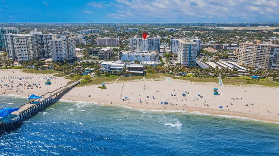 Aerial view of beachfront buildings with a sandy beach and ocean in the foreground.