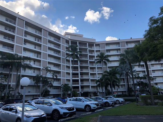Front view of a multi-story apartment building with balconies and parking area.
