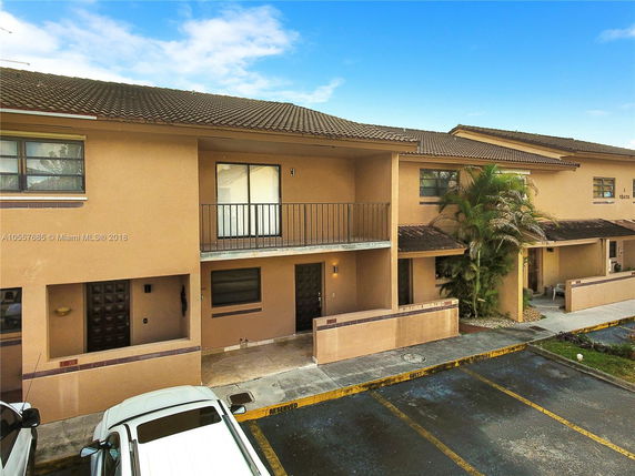Front view of a two-story townhouse with balconies and parking spaces.