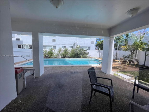 View of a swimming pool area with surrounding seating and plants.