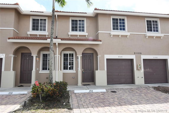 Front view of a two-story townhouse with garage and arched entryway.