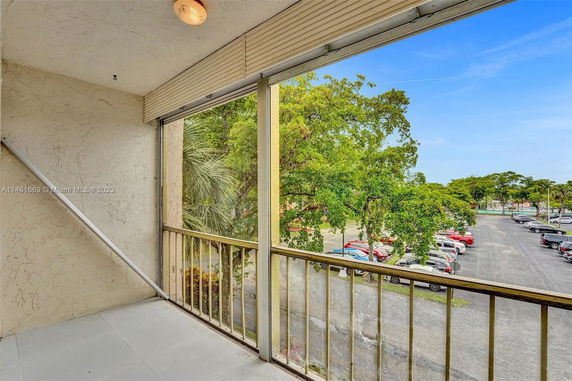 View from a building balcony showing a parking area and greenery.