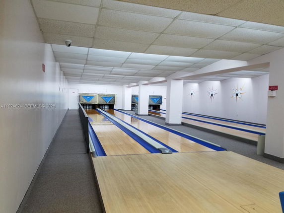 Indoor bowling alley with multiple lanes and a carpeted walkway.