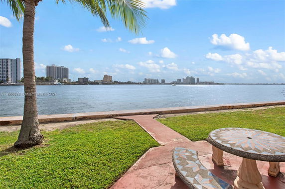 View of a waterfront with buildings and a palm tree.