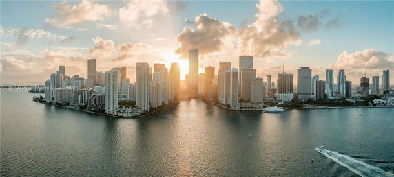 Panoramic view of a city skyline with tall buildings and a body of water.