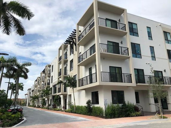 Front view of a modern multi-story apartment building with balconies.